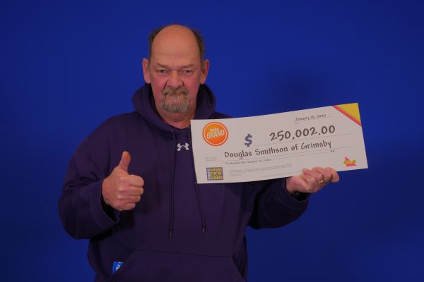 Man holding winning OLG daily grand ticket with thumbs up.