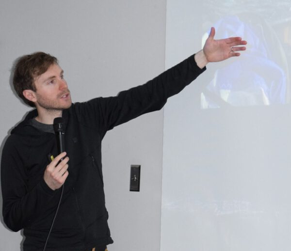 A young man gestures to a projected photo.