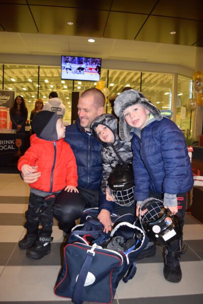 Dad and his three boys get skating equipment on.