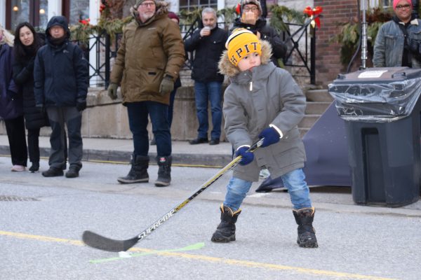 A young boy swings his hockey stick to hit a puck made out of ice.