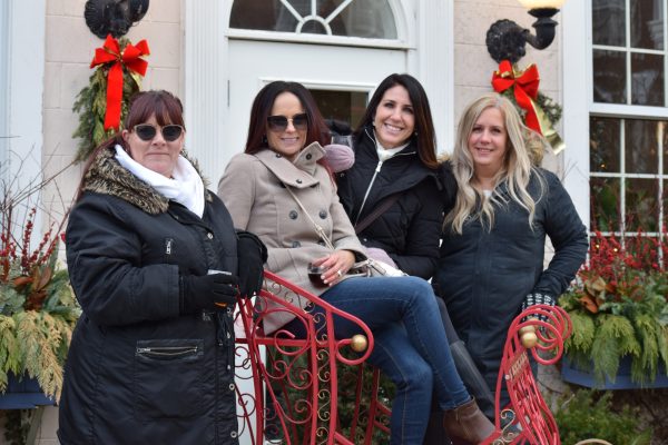 Four women pose together on a bench made to look like a sleigh.