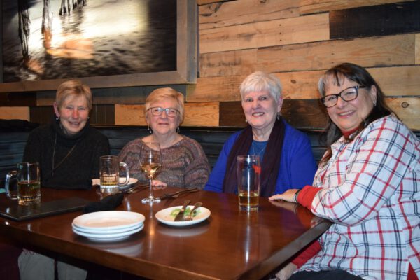 Four older ladies sit around a table.