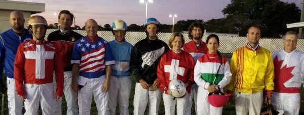 Eleven horse race driver wearing outfits bearing their national flag stand in a row.