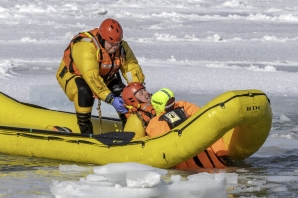 A firefighter in an inflatable dingy pulls up a mannikin from icy Lake Ontario.